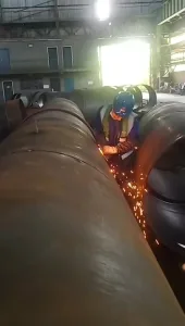 Welder working on large pipes with sparks flying
