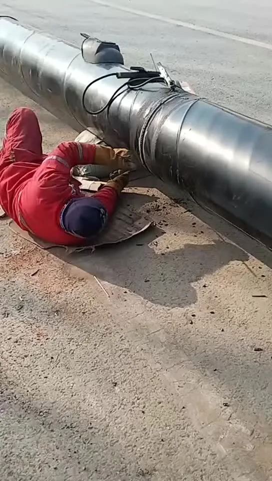 A field welder in protective gloves working on large pipes — real-world conditions where aramid stitching proves its durability.