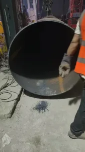 A gloved hand guiding steel pipe during fabrication — contact with hot or freshly welded metal is one of the leading causes of welder hand burns.
